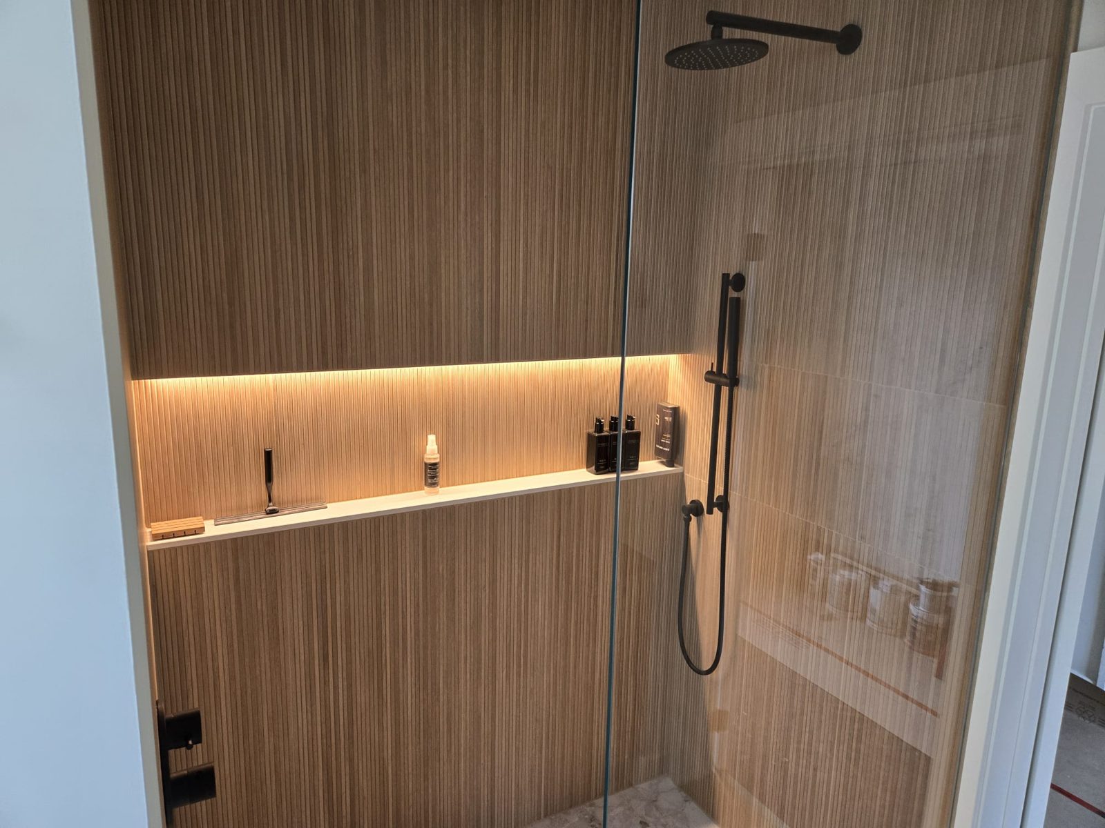 Shower with a lit wall niche and wood slat tile, by HausPower